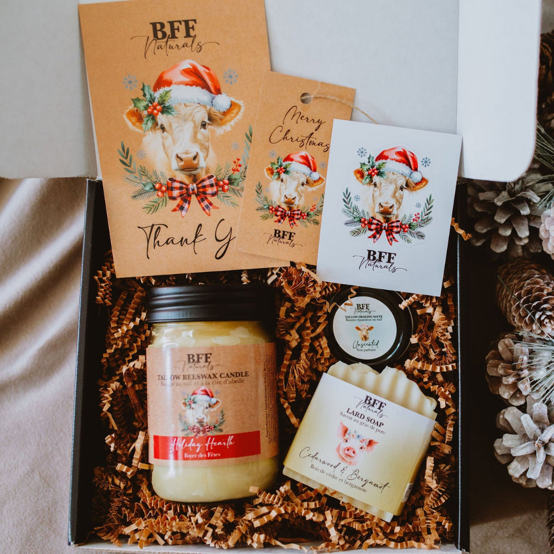 Gift set with candles and decorative items, featuring pinecones and flowers, on a neutral background.